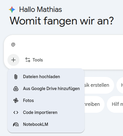Screenshot der Benutzeroberfläche von Google Gemini. Oben steht „Hallo Mathias“ und darunter die Frage „Womit fangen wir an?“. Unter dem Eingabefeld ist das geöffnete Plus-Menü („+“) sichtbar. Es zeigt die Optionen „Dateien hochladen“, „Aus Google Drive hinzufügen“, „Fotos“, „Code importieren“ und „NotebookLM“.